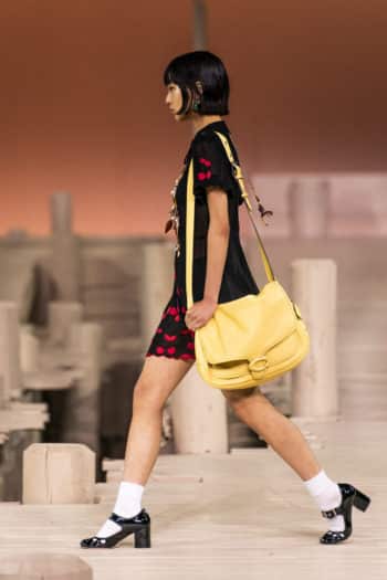 Coach model with yellow shoulder back and black and red mini dress SS23